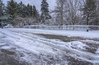 a bunch of snow is piled onto the road in front of a wooden bridge near a forest