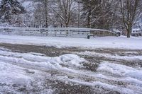 a bunch of snow is piled onto the road in front of a wooden bridge near a forest