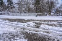 a bunch of snow is piled onto the road in front of a wooden bridge near a forest