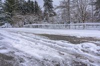 a bunch of snow is piled onto the road in front of a wooden bridge near a forest