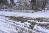 a bunch of snow is piled onto the road in front of a wooden bridge near a forest