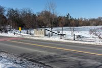 a traffic signal sits in the snow near the road side at a stop sign near a lake