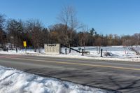 a traffic signal sits in the snow near the road side at a stop sign near a lake