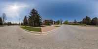 a view of the intersection and street from inside a fish eye lens, with a house in the distance