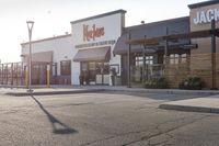 a large, open restaurant next to a parking lot with no cars on it and there are store fronts on either side