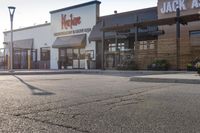 a large, open restaurant next to a parking lot with no cars on it and there are store fronts on either side