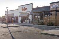 a large, open restaurant next to a parking lot with no cars on it and there are store fronts on either side