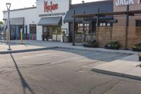 a large, open restaurant next to a parking lot with no cars on it and there are store fronts on either side