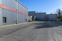 there is an industrial building behind this empty street with parking spots and a building that has a large garage on the other side