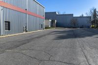 there is an industrial building behind this empty street with parking spots and a building that has a large garage on the other side