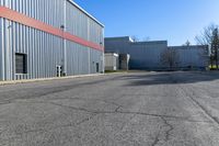 there is an industrial building behind this empty street with parking spots and a building that has a large garage on the other side