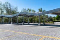 empty parking lot with covered seating with open area for the buses or passengers, next to trees and benches