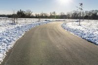 a paved road that has some snow on top of it in the middle of the day