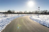 a paved road that has some snow on top of it in the middle of the day