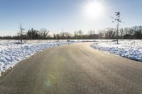 a paved road that has some snow on top of it in the middle of the day