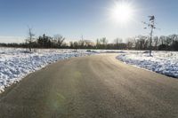 a paved road that has some snow on top of it in the middle of the day