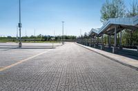 a view of a public transit station across a cobbled stone walkway in front of a large green field