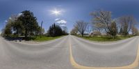 a fish eye lens view of a road that runs through the field and is partially filled with green grass and bushes