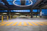 an empty parking space with yellow lines running between columns and a circular light fixture overhead