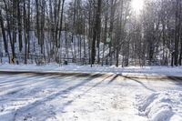 snow covers the road, and a yellow caution sign is out in the woods behind it