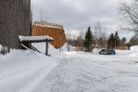 two cars parked next to a wooden covered building on the side of the road in winter