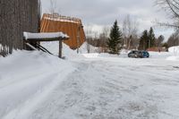 two cars parked next to a wooden covered building on the side of the road in winter