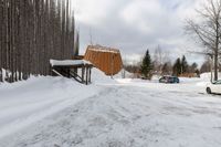 two cars parked next to a wooden covered building on the side of the road in winter