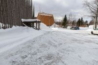 two cars parked next to a wooden covered building on the side of the road in winter