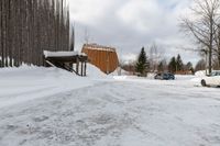 two cars parked next to a wooden covered building on the side of the road in winter