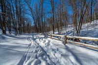 a path is partially covered in fresh snow during the winter months with a wooden fence on both sides