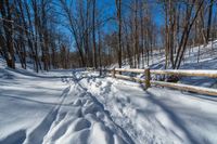 a path is partially covered in fresh snow during the winter months with a wooden fence on both sides