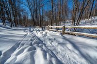 a path is partially covered in fresh snow during the winter months with a wooden fence on both sides