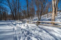 a path is partially covered in fresh snow during the winter months with a wooden fence on both sides