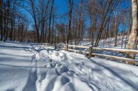 a path is partially covered in fresh snow during the winter months with a wooden fence on both sides