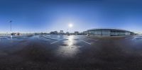 an empty parking lot is on the side of the road in the sunlight by a large glass building