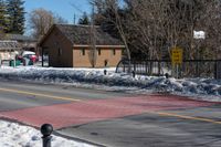 a couple of traffic lights sitting on the side of the road next to snow covered sidewalk