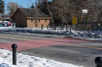 a couple of traffic lights sitting on the side of the road next to snow covered sidewalk