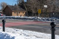 a couple of traffic lights sitting on the side of the road next to snow covered sidewalk