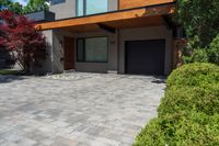 an driveway area and garage that has stone and gravel with a large front porch and garage on the other side with wood on top