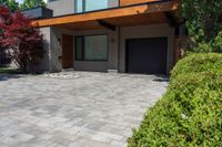 an driveway area and garage that has stone and gravel with a large front porch and garage on the other side with wood on top