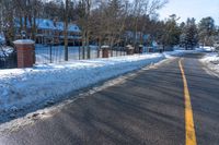 a road in the winter next to houses and trees with snow on it's sides