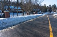 a road in the winter next to houses and trees with snow on it's sides