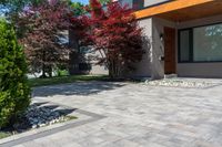 the front view of this modern home shows brick walkway, stone pavers, and colorful trees