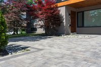 the front view of this modern home shows brick walkway, stone pavers, and colorful trees