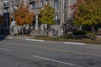 a bus is driving on the road near some buildings and trees in the falltime