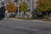 a bus is driving on the road near some buildings and trees in the falltime