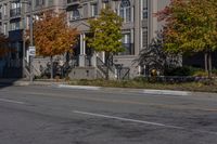 a bus is driving on the road near some buildings and trees in the falltime