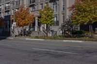 a bus is driving on the road near some buildings and trees in the falltime