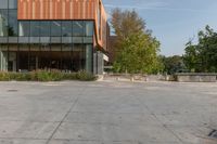 the entrance to a tall office building is shown with trees and shrubs lining the path