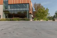 the entrance to a tall office building is shown with trees and shrubs lining the path